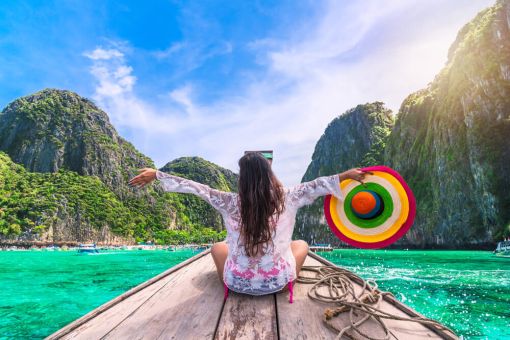 Traveller on front of a boat wth open arms looking a islands in Thailand